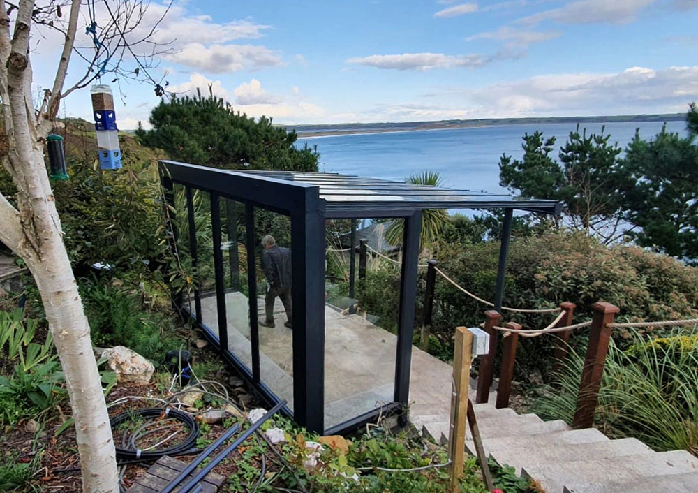 Fixed glass wall veranda perched on a coastal cliff with panoramic ocean view and coastal planting