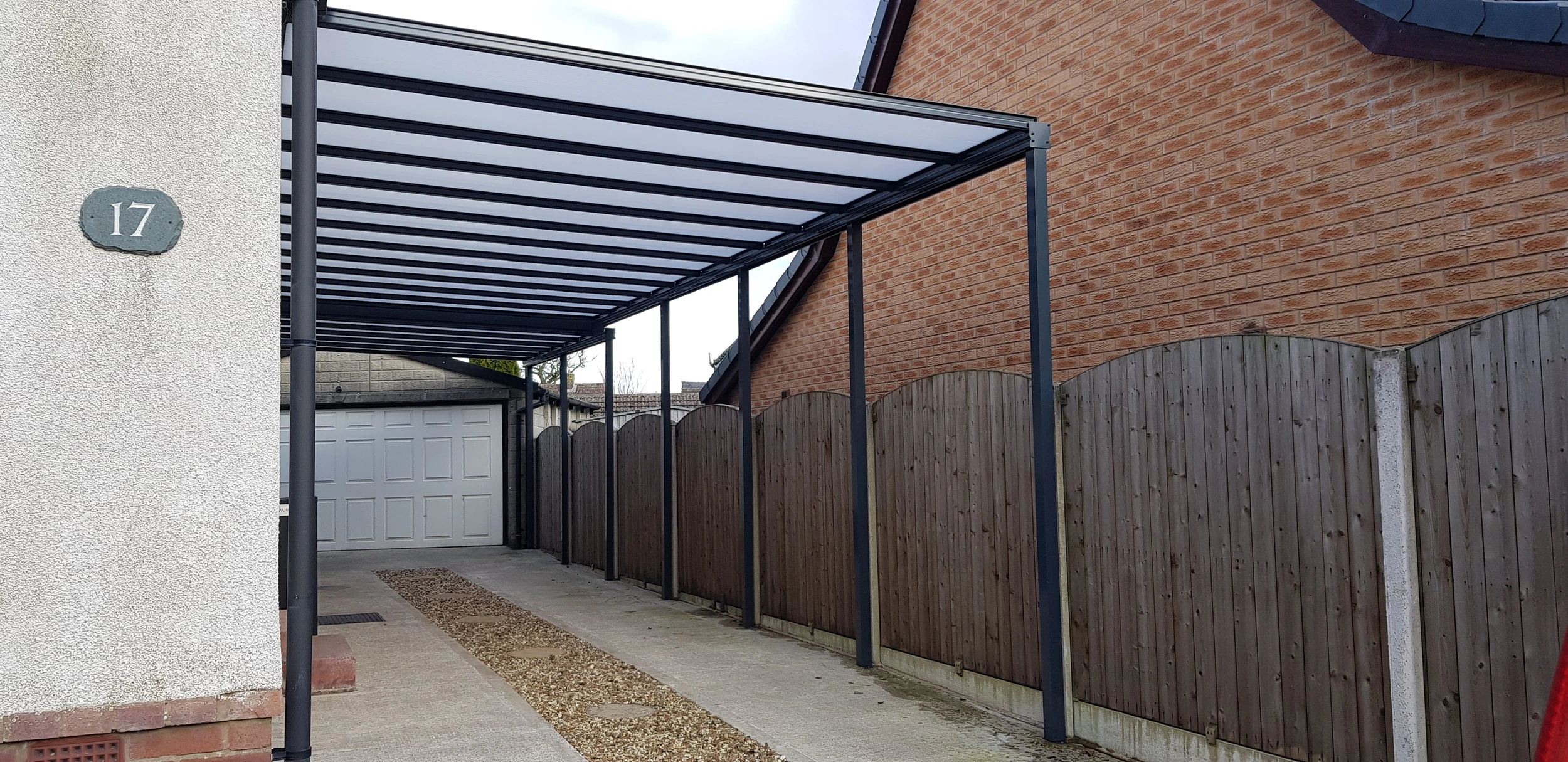Harbour aluminium carport in anthracite grey fitted alongside a red-brick English home