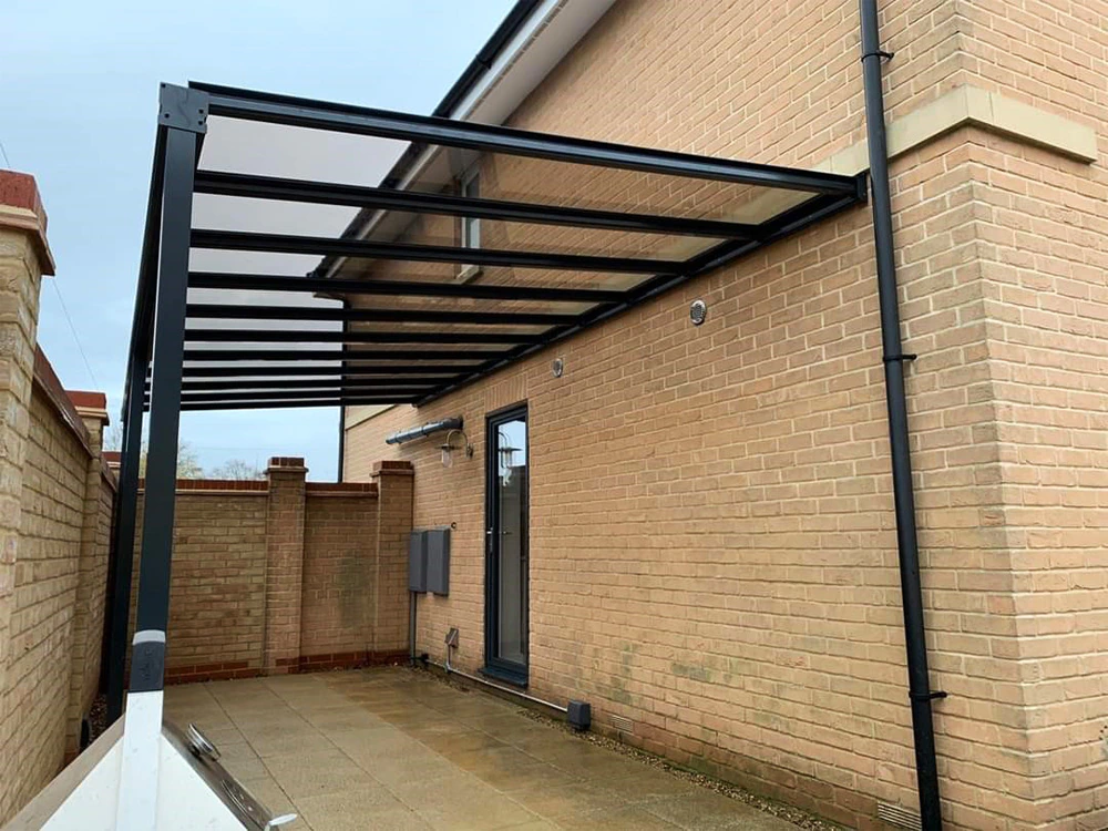 Harbour aluminium carport in anthracite grey at the rear of a tan-brick English home