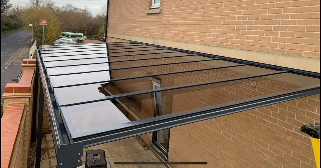 Harbour carport covering a paved patio alongside a British home