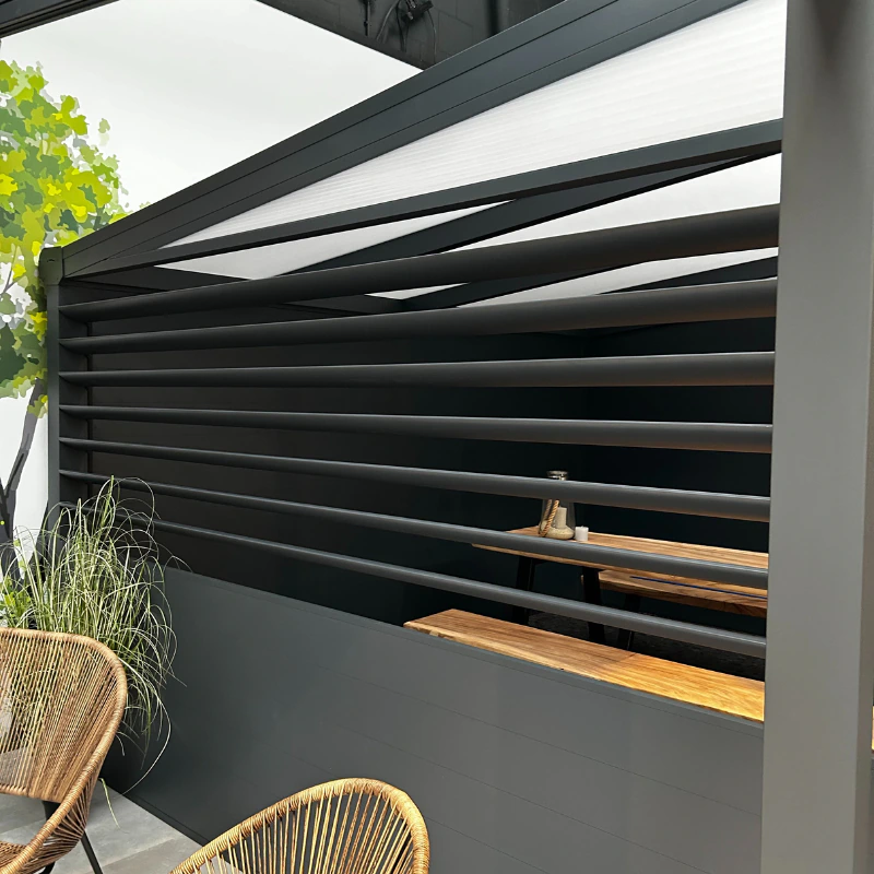 Angled anthracite louvred wall on a veranda shielding a wooden bar counter and wicker chairs