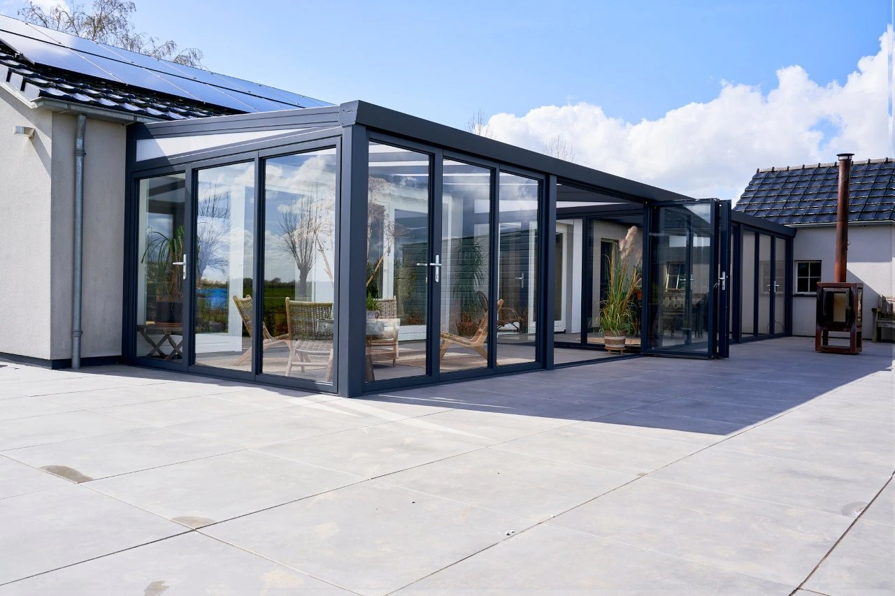 Large L-shaped slide and tilt veranda wrapping around a white single-storey bungalow with solar panels
