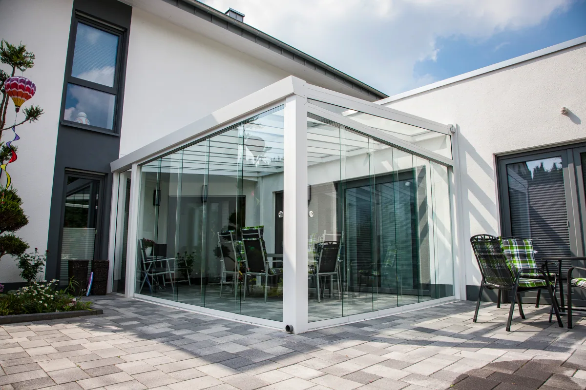 Lockable sliding glass doors enclosing a corner veranda on a modern white home with patio seating