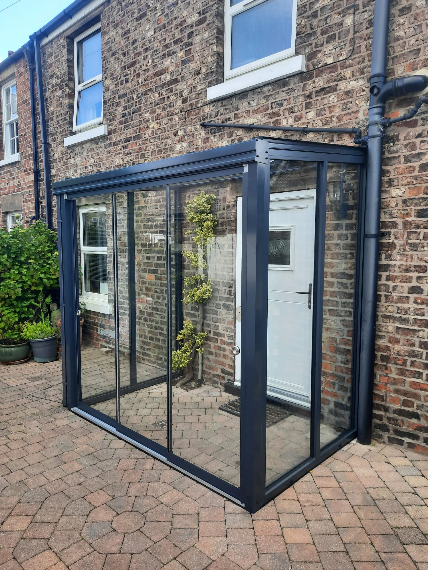Compact sliding glass door porch enclosure on a York-brick terrace house with block-paved patio